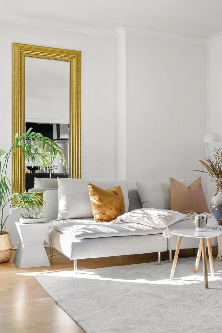 Minimalistisch interieur met bank en grote gouden spiegel.
